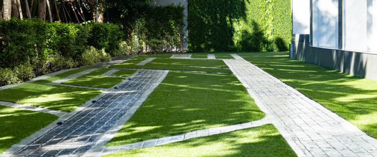Jardín exterior con césped artificial verde instalado alrededor de piscina y zona de descanso