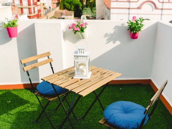 Césped artificial en terraza de ático con mobiliario exterior y vistas a ciudad