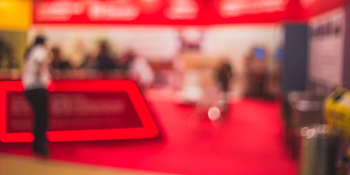 Stand ferial con moqueta ferial roja corporativa instalada en pabellón de exposiciones